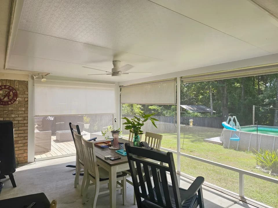 Screened dining porch with ceiling fan and two roller sun shades partway lowered over the pool-view opening, Semmes AL.