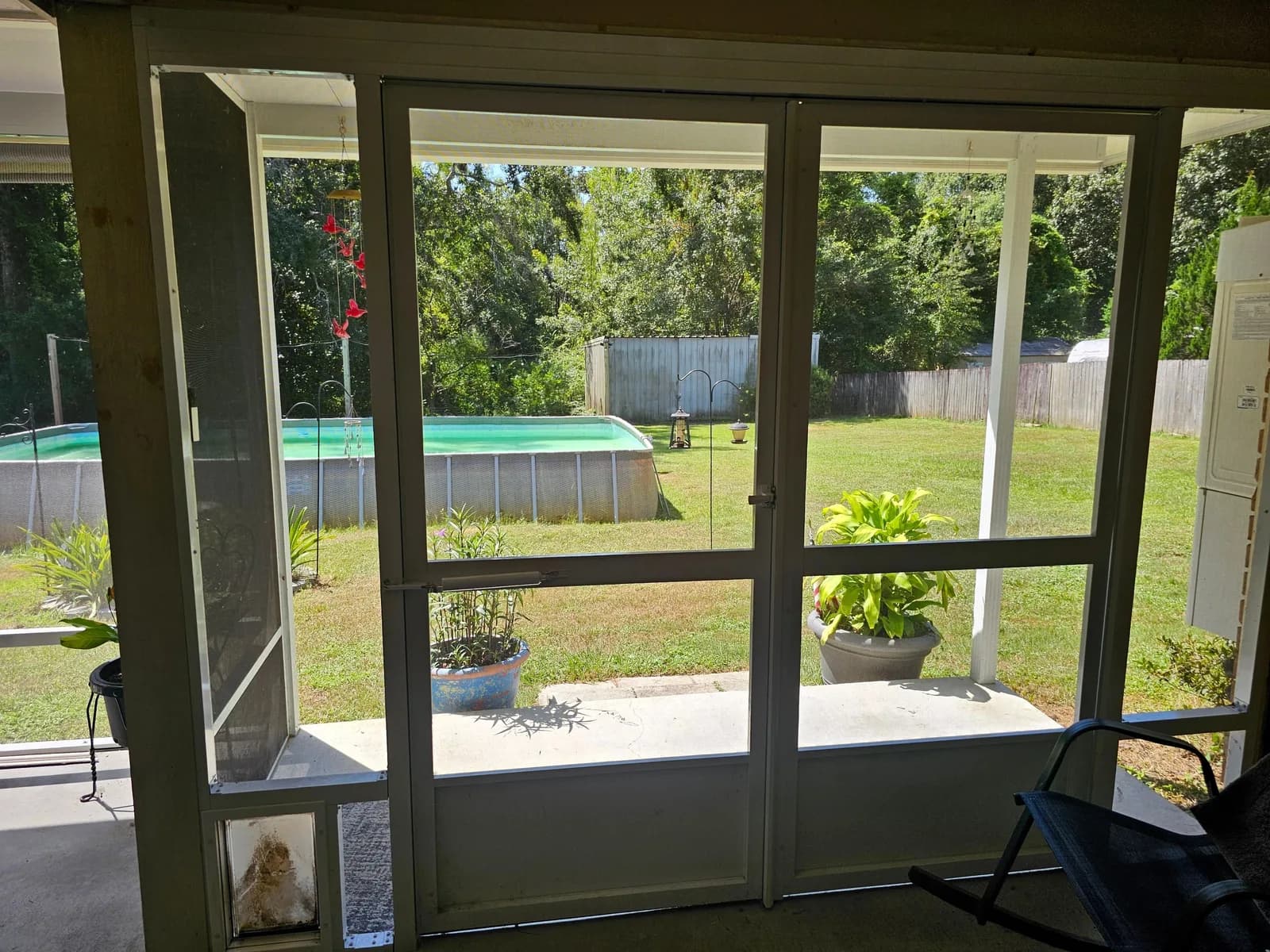 White aluminum double screen doors with a built-in pet door, above-ground pool visible beyond, Semmes AL.