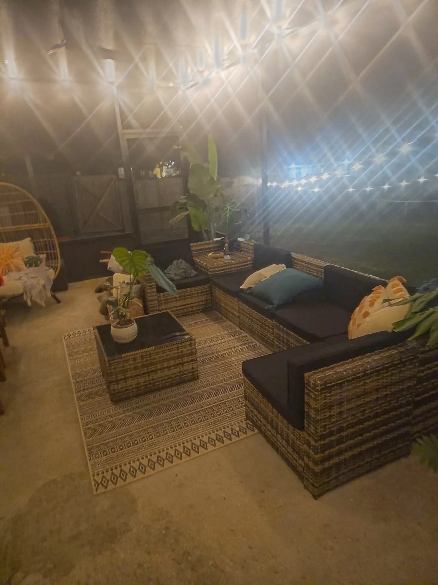 Screen room interior at night with string lights, wicker sectional seating, and an egg chair, Daphne AL.