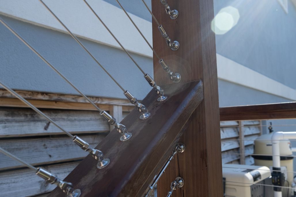 Close-up of Ram Tail stainless steel cable railing hardware fittings on a wood post.