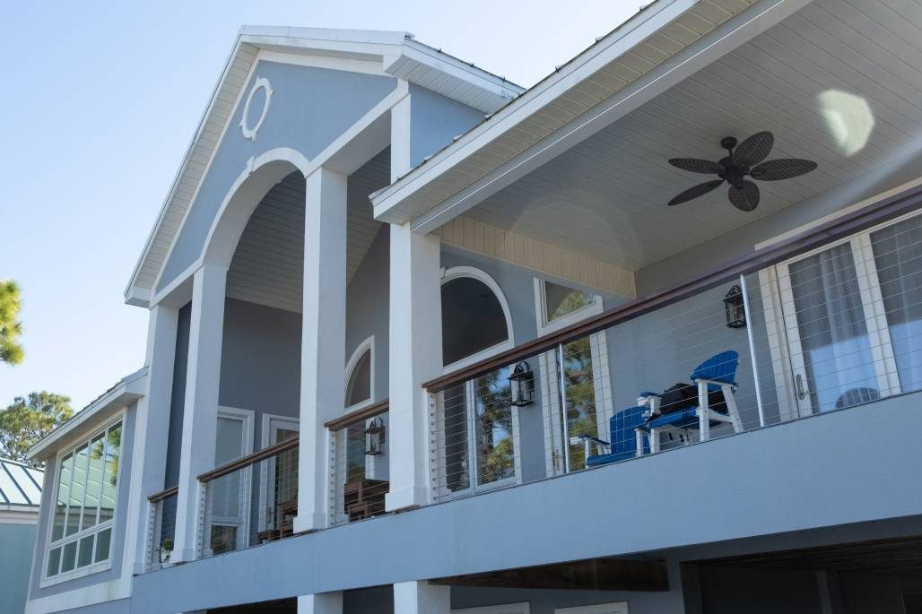 Ram Tail stainless cable railing along a covered balcony with a ceiling fan overhead.