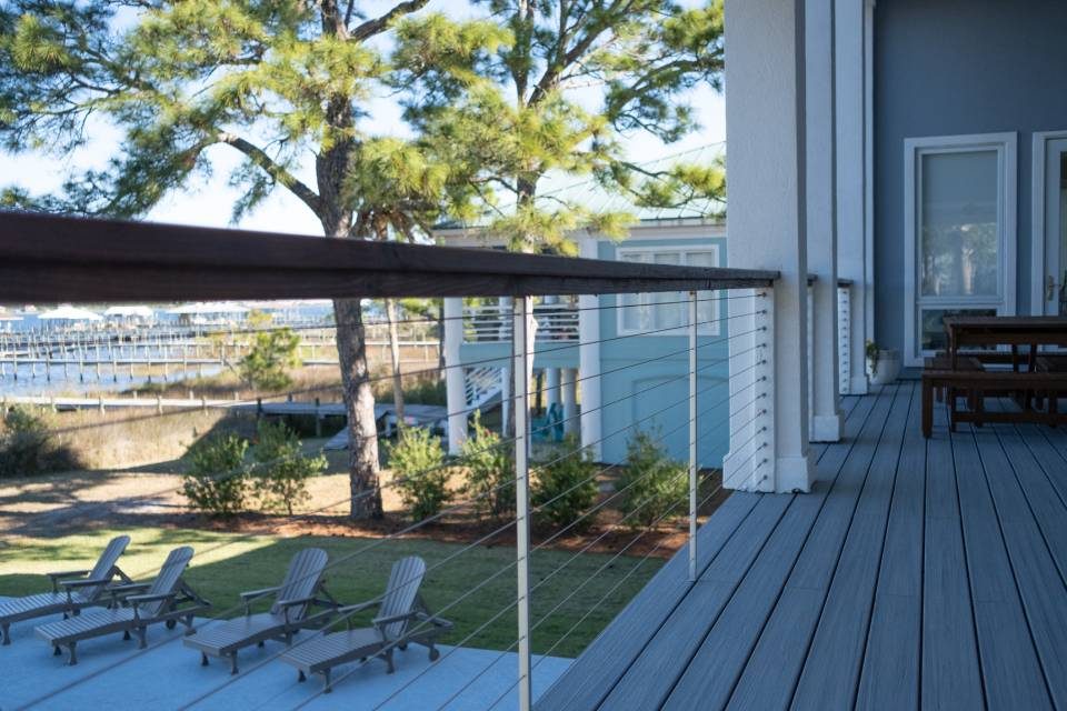 Ram Tail stainless cable railing along a deck with a waterfront view and lounge chairs.