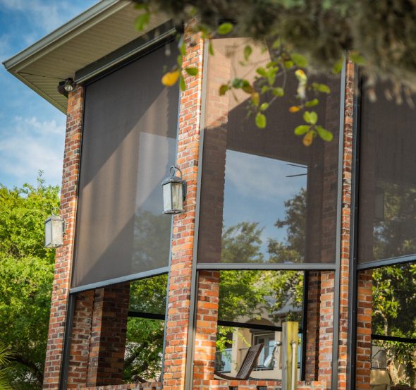 SunPro motorized solar screens lowered over a brick porch corner.