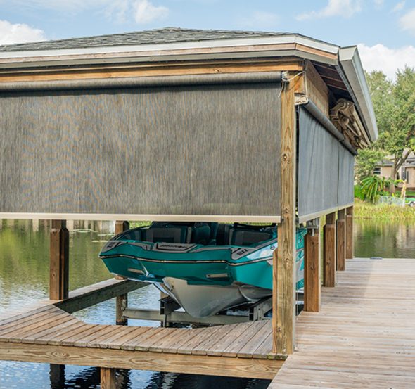 SunPro motorized screens lowered around a boathouse over a docked boat.
