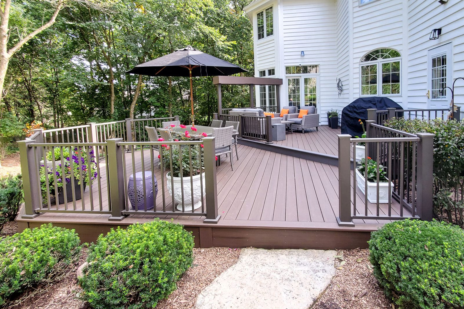 Bronze Westbury aluminum railing with ornamental balusters around a deck seating and dining area.